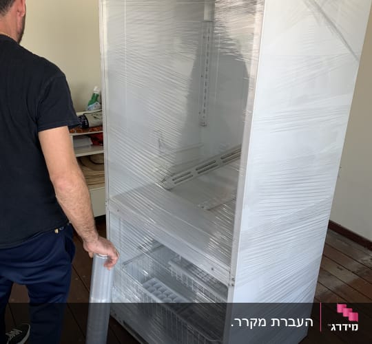 אדם עוטף מקרר בניילון נצמד להעברה